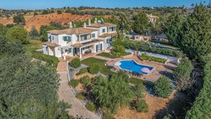 Una casa grande de dos pisos con piscina y un jardín bien cuidado.
