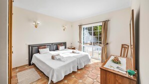 Habitación de hotel con dos camas, una mesita, una silla, una ventana con cortinas y vistas al exterior.