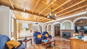 Un amplio salón con un alto techo de madera, una chimenea y un piso de baldosas de piedra.