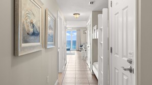 A hallway with framed artwork, white doors, and a view to a balcony. - 4TH FLOOR! GREAT DECOR! OUTSTANDING VIEWS! (Panama City Beach)