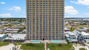 A high-rise hotel with multiple balconies, a swimming pool, and a view of the surrounding area. - 4TH FLOOR! GREAT DECOR! OUTSTANDING VIEWS! (Panama City Beach)