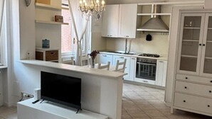 Una cocina moderna con gabinetes blancos, estufa integrada y una araña.