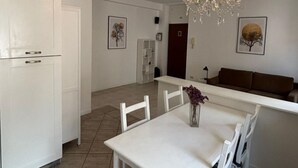 Una cocina moderna con armarios blancos, una mesa de comedor con sillas, una araña y obras de arte en las paredes.