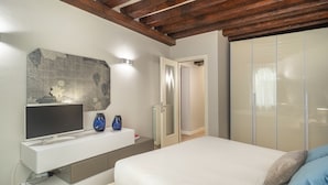 Un dormitorio con una cama, un televisor, una consola blanca y una obra de arte de piedra en la pared.