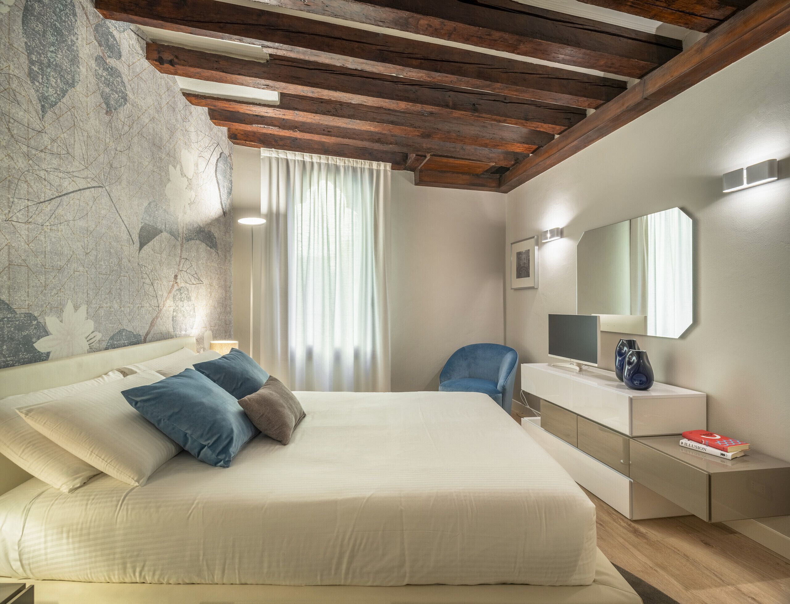 Une chambre à coucher avec un grand lit, un bureau, une chaise, une télévision et un miroir.