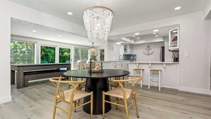 A modern kitchen with white cabinets, a round dining table with chairs, and a chandelier. - Resort Backyard! Heated Pool! Pool Table! PingPong (Largo)
