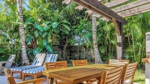 An outdoor wooden table and chairs set in a tropical garden with lush greenery and a wooden pergola overhead. - Resort Backyard! Heated Pool! Pool Table! PingPong (Largo)