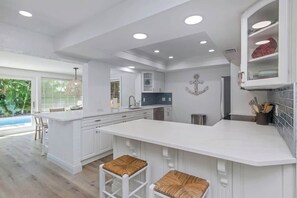A modern kitchen with white cabinetry, a central island, and a view of a pool. - Resort Backyard! Heated Pool! Pool Table! PingPong (Largo)