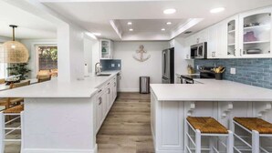 A modern kitchen with white cabinetry, a central island, and bar stools. - Resort Backyard! Heated Pool! Pool Table! PingPong (Largo)
