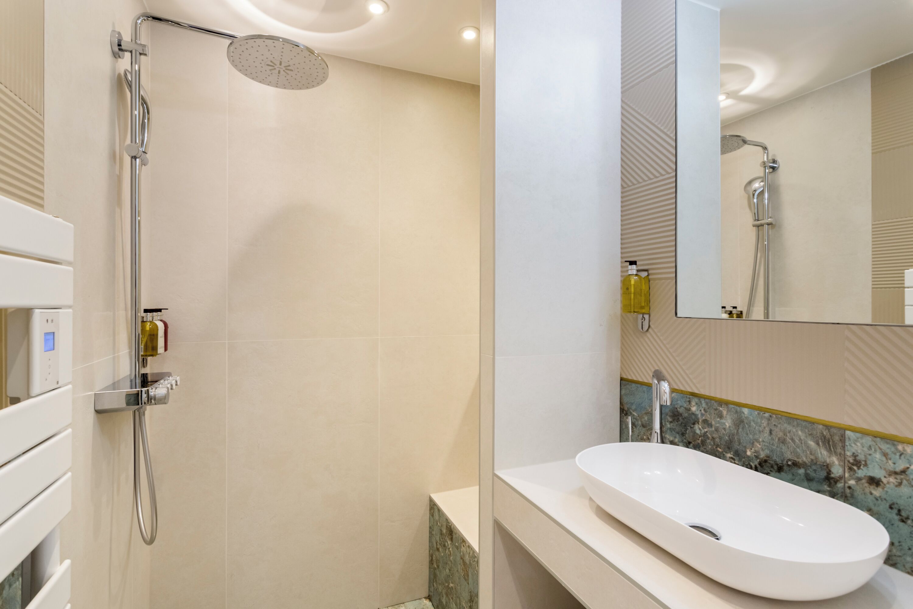 A modern bathroom with a walk-in shower, a white sink, and a mirror.