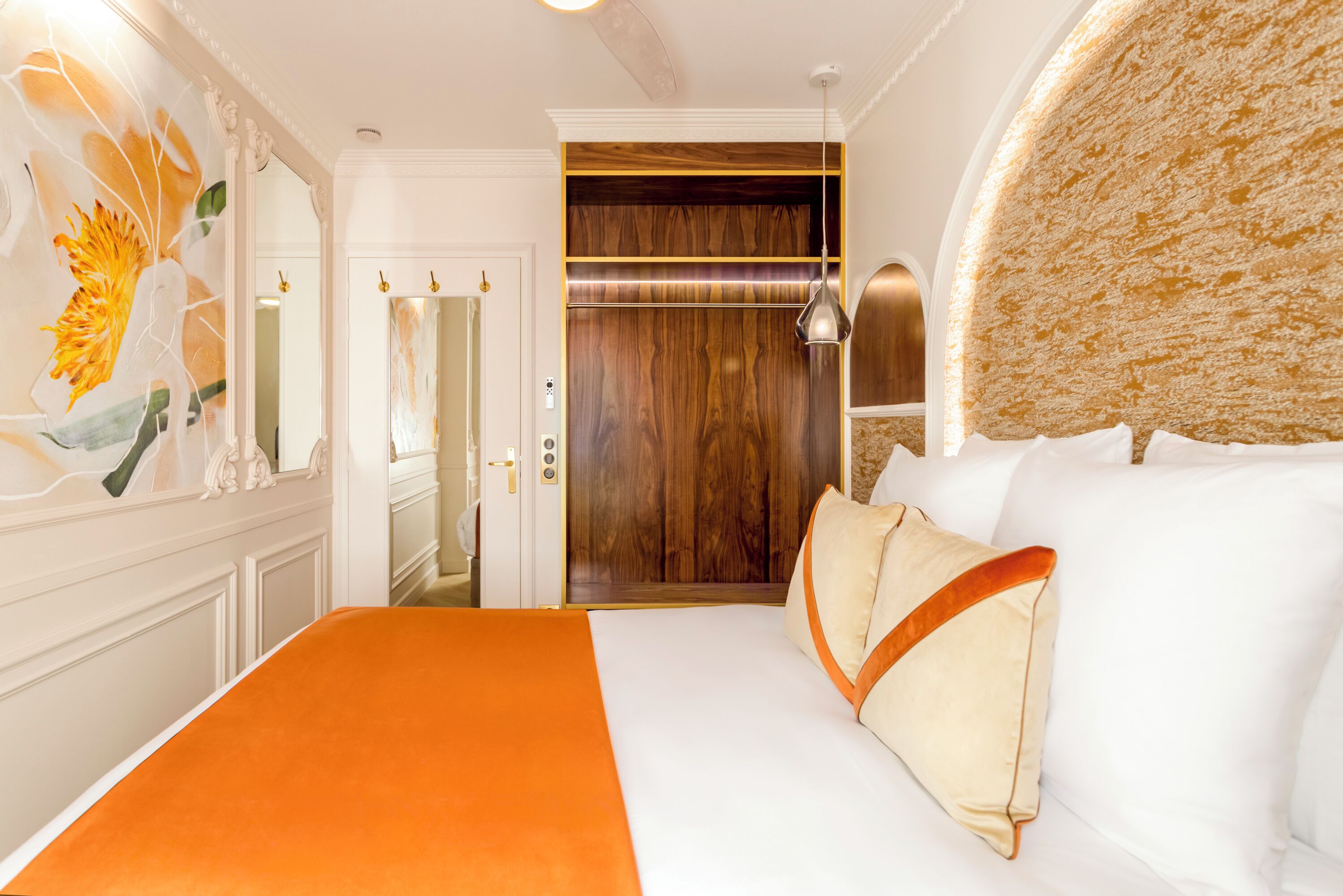 Une chambre d’hôtel avec un grand lit, une armoire en bois et un miroir.