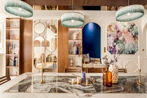 A modern interior with a marble table, decorative mirrors, and a blue accent wall.