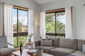 Un salon avec un canapé, un fauteuil, une table et des plantes en pot.