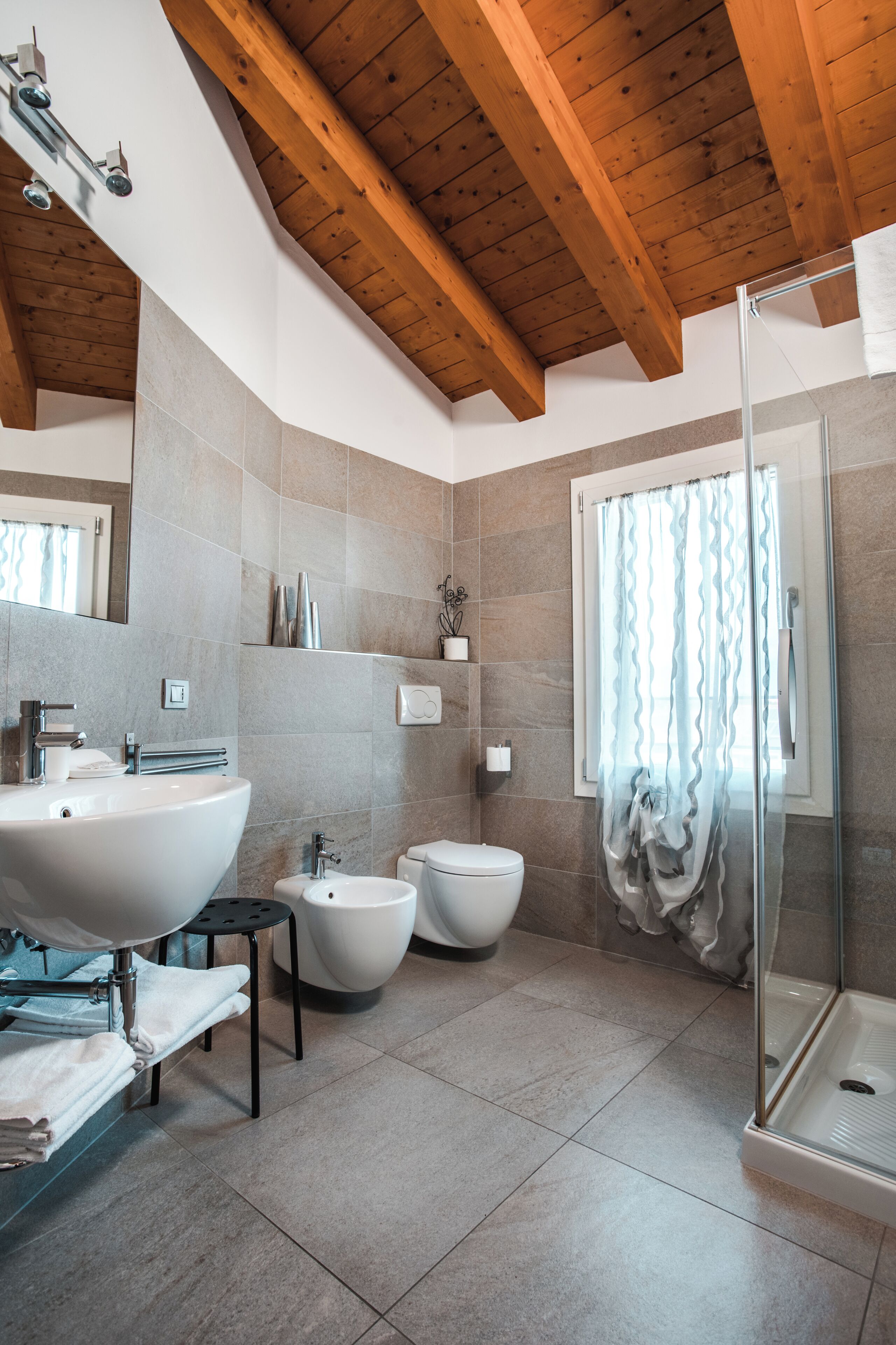 A modern bathroom with a large sink, bidet, and glass shower enclosure.