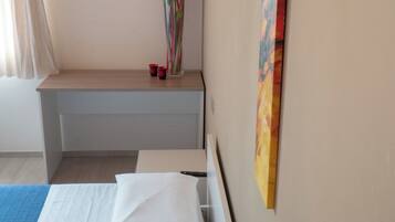 Ein Hotelzimmer mit einem Bett, einem Schreibtisch, einer Blumenvase und zwei Bildern an der Wand.