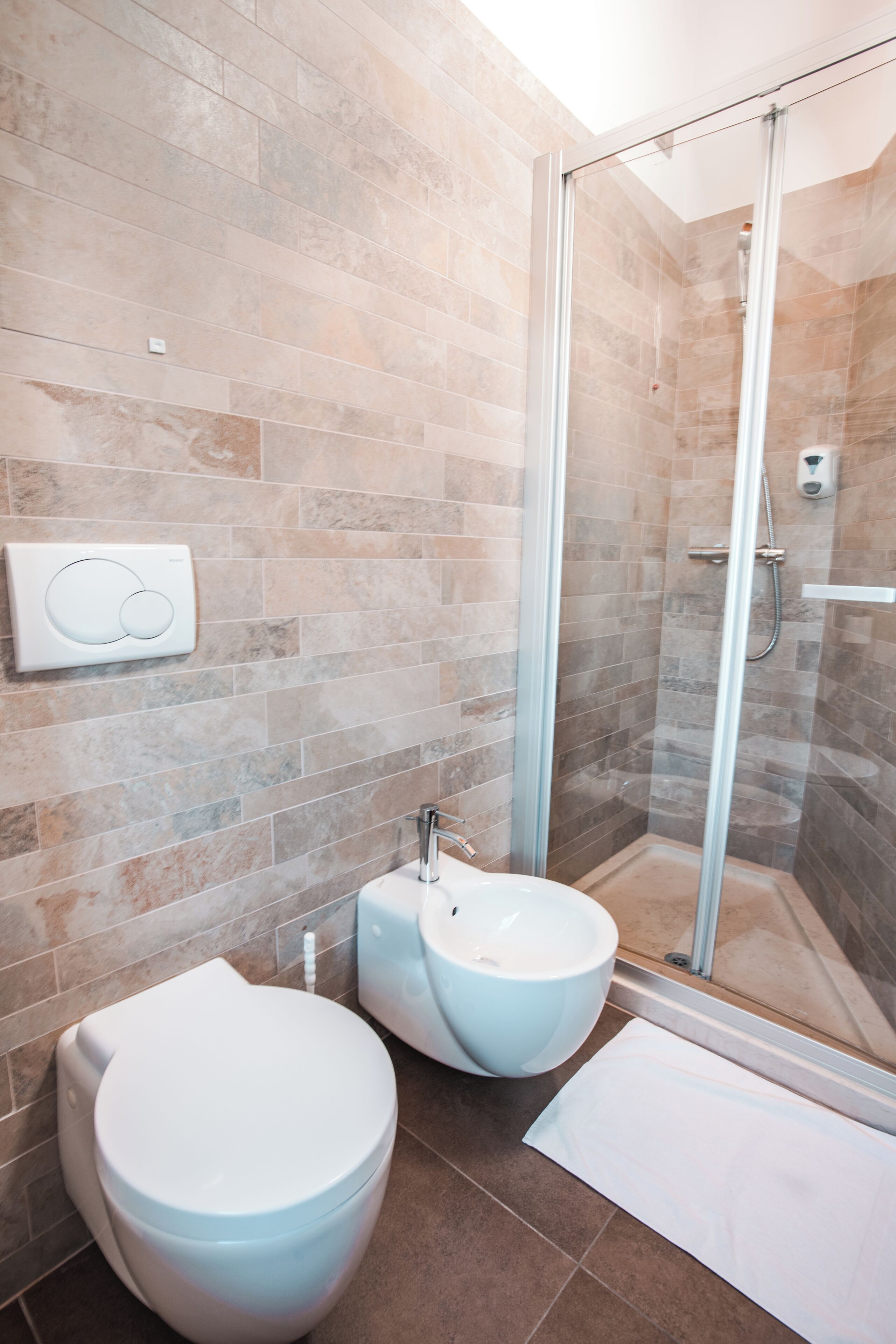 A modern bathroom with a toilet, bidet, and glass-enclosed shower.