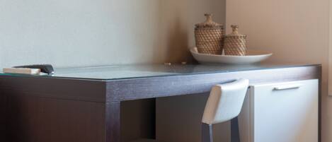 A modern desk with a glass top, a white chair, and decorative items on the side.