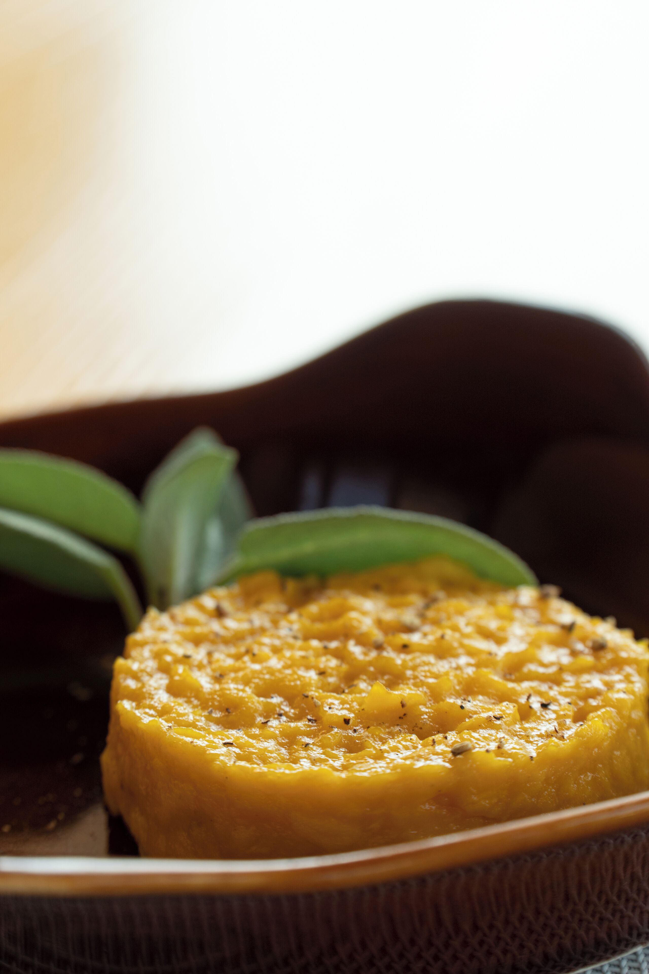 A close-up of a dish with a yellow sauce, possibly a curry, in a textured bowl.
