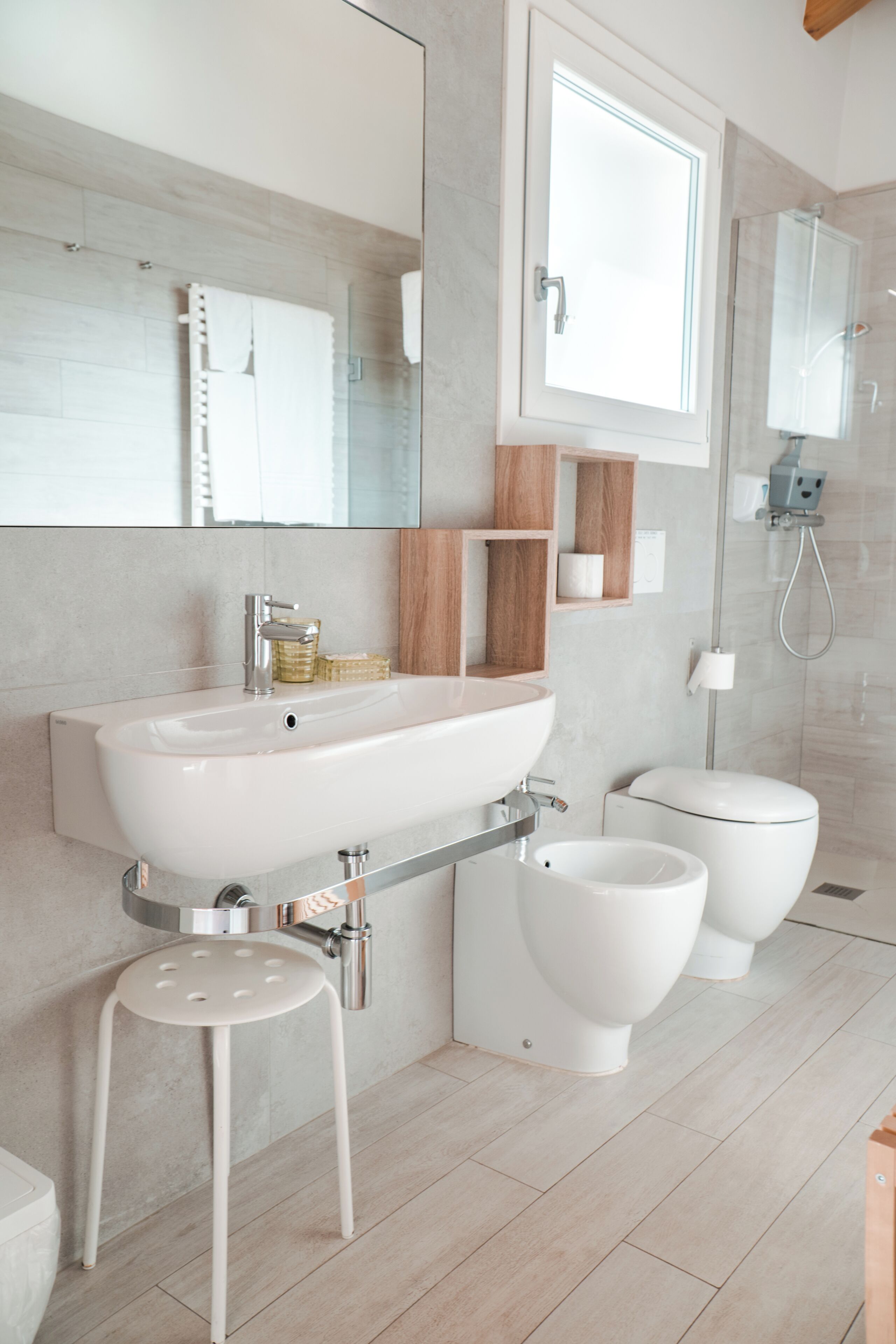A modern bathroom with a large sink, two toilets, a shower, and a mirror.