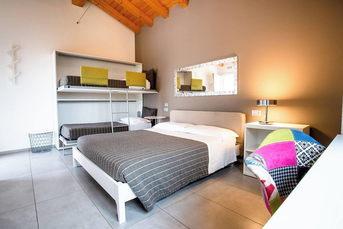 A bedroom with a bed, a nightstand, a mirror, and built-in shelving.