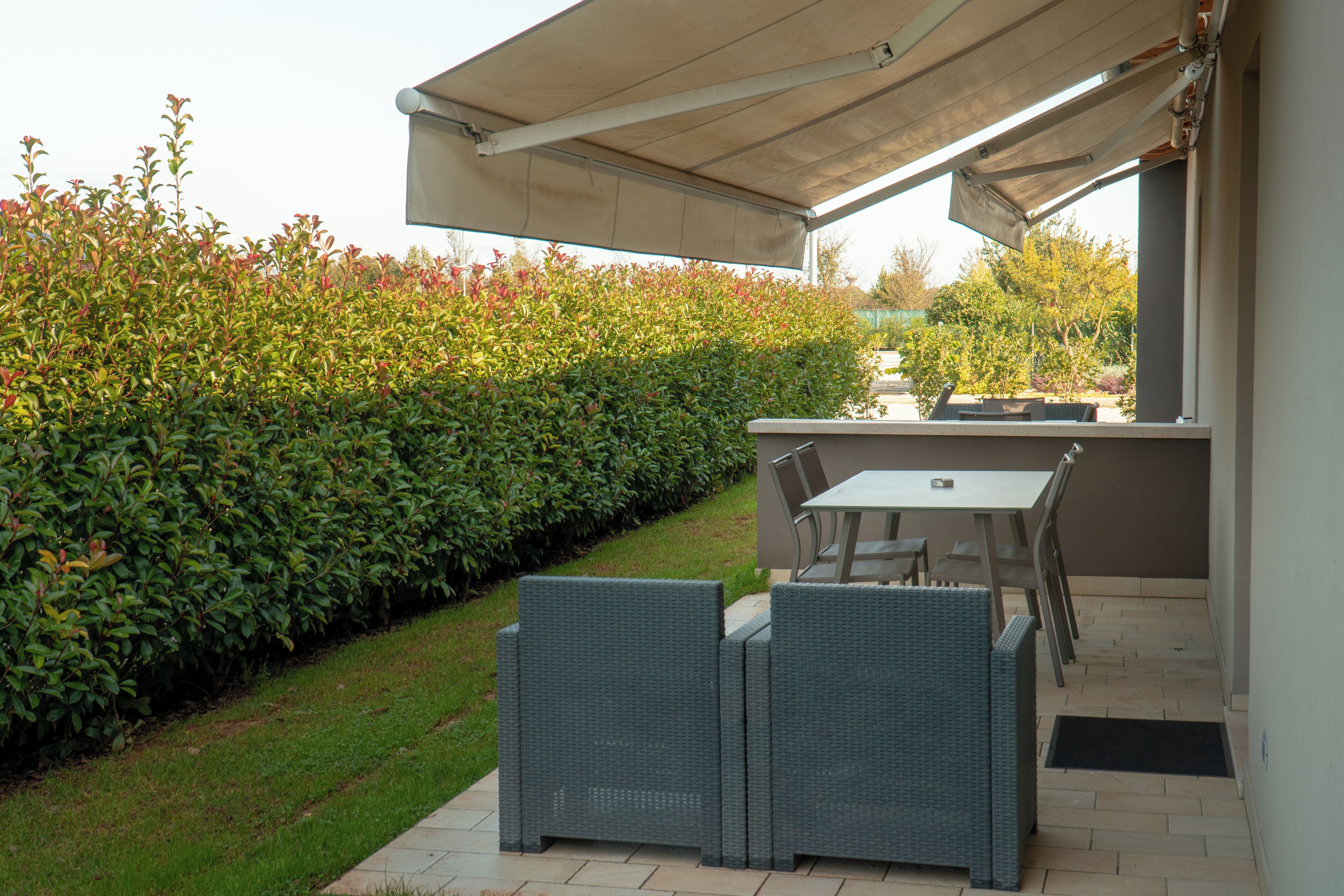 An outdoor patio with wicker furniture, a table, and a covered area.