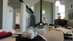 A modern dining area with a fireplace, white furniture, and a tray with cups and a teapot. - Magrine Castelfranco Veneto  (Castelfranco Veneto)