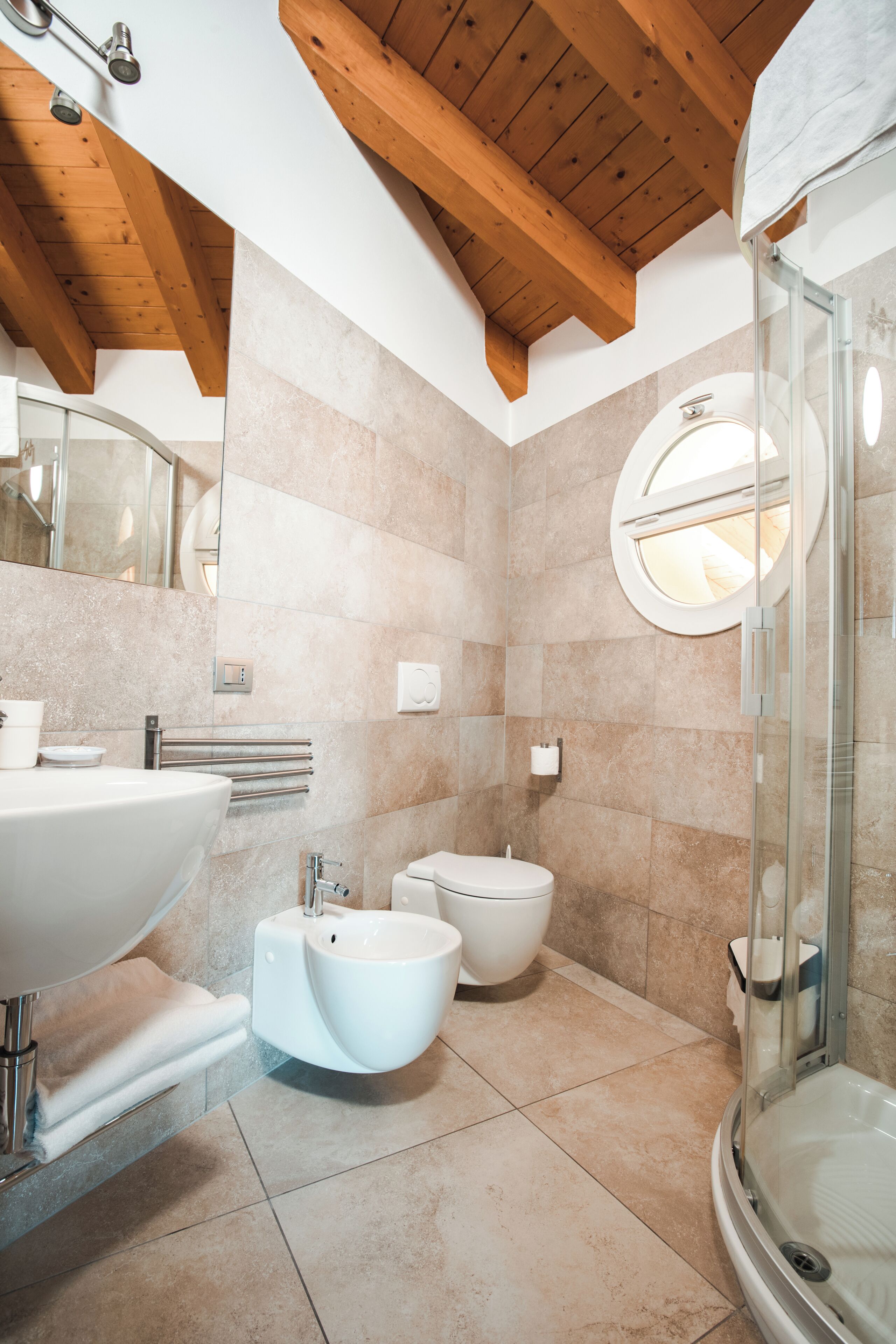 Un baño moderno con un lavamanos grande, un bidé, un inodoro y una ducha con cerramiento de vidrio.
