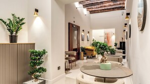 Un interior moderno con una mesa redonda, sillas, una planta en maceta y una puerta de madera.