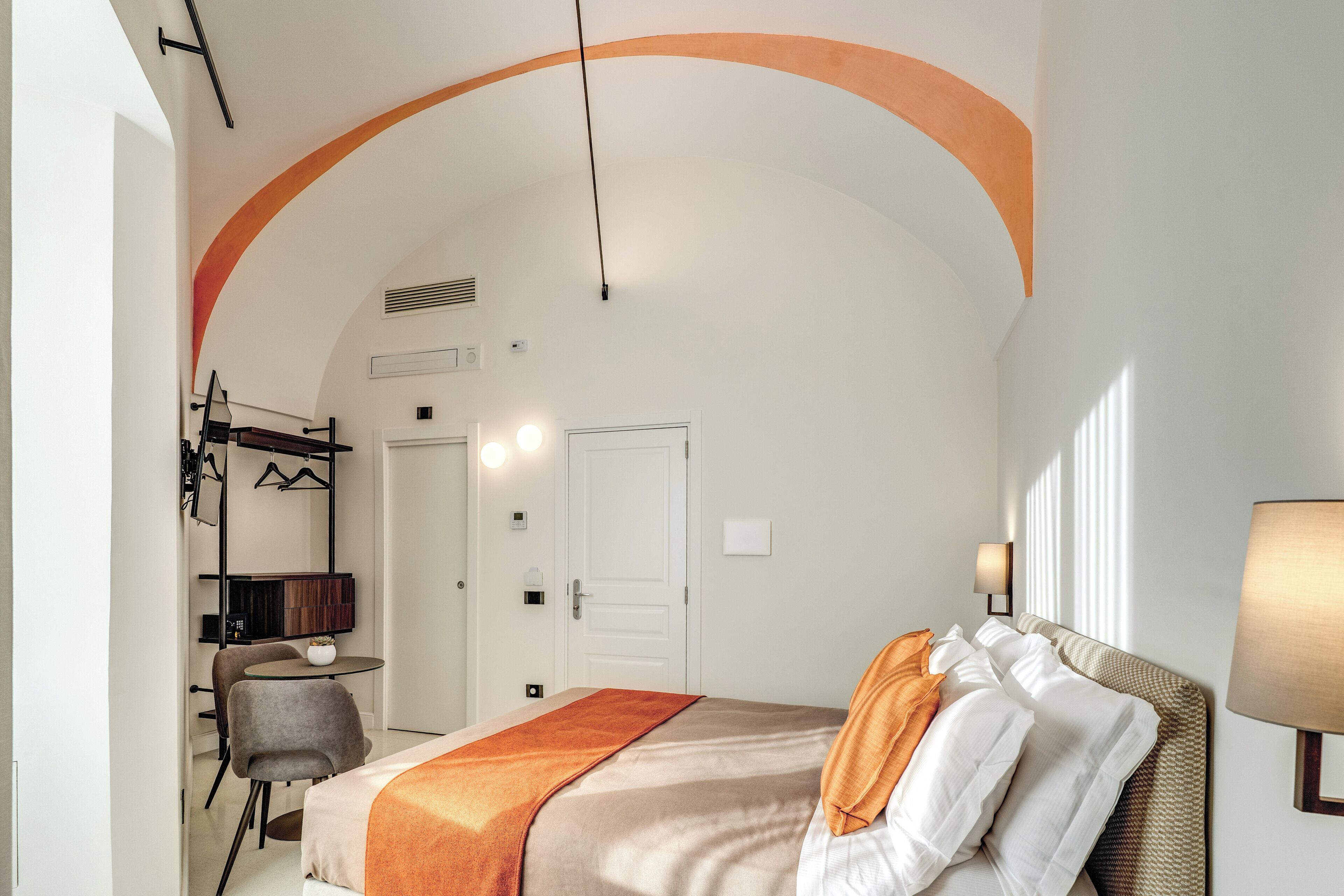 A hotel room with a bed, a desk, a chair, and a small table.