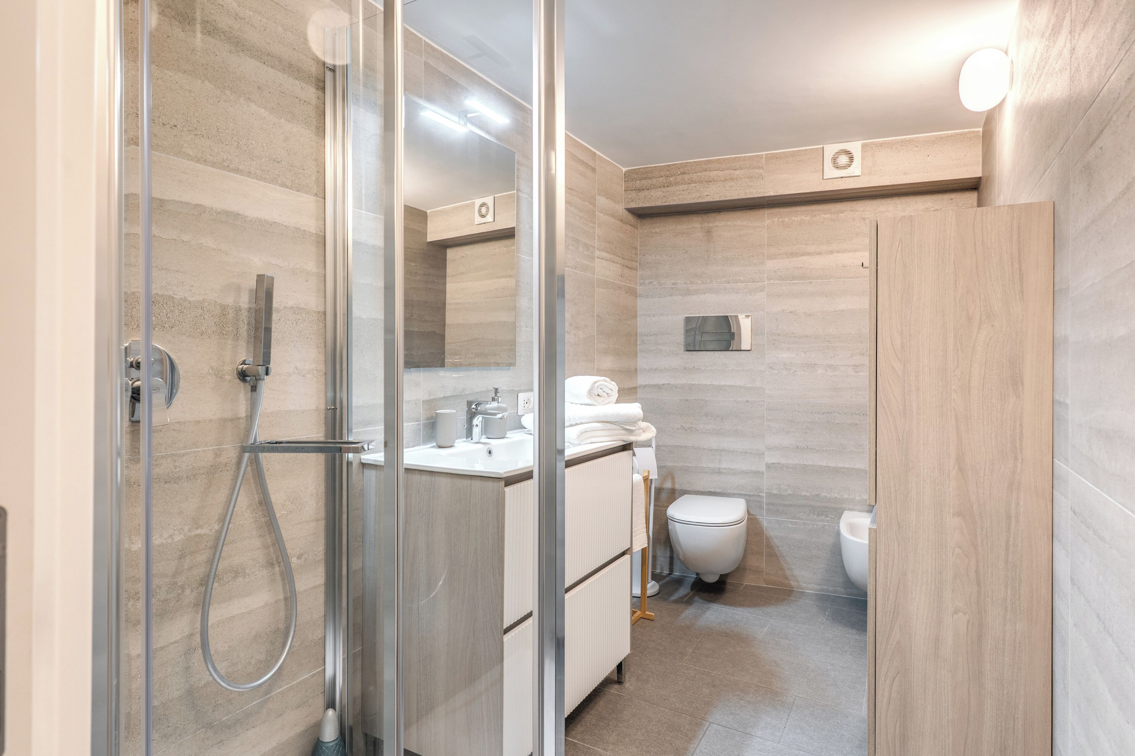 A modern bathroom with a glass shower enclosure, a white sink, and a toilet.