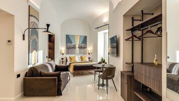 A modern hotel room with a bed, a sofa, a dining table, and a mirror.