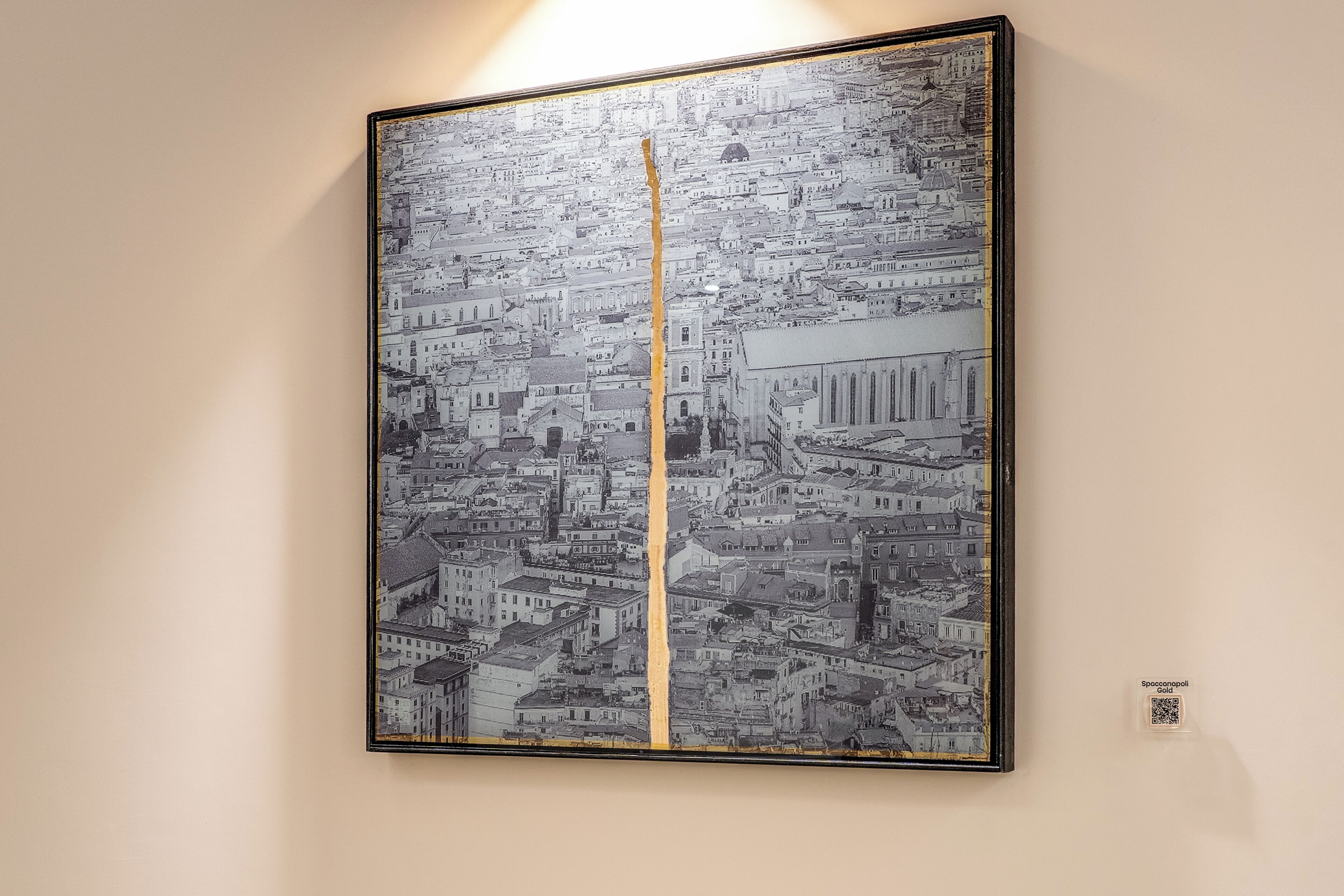 A framed black and white cityscape artwork with a vertical crack running through it.