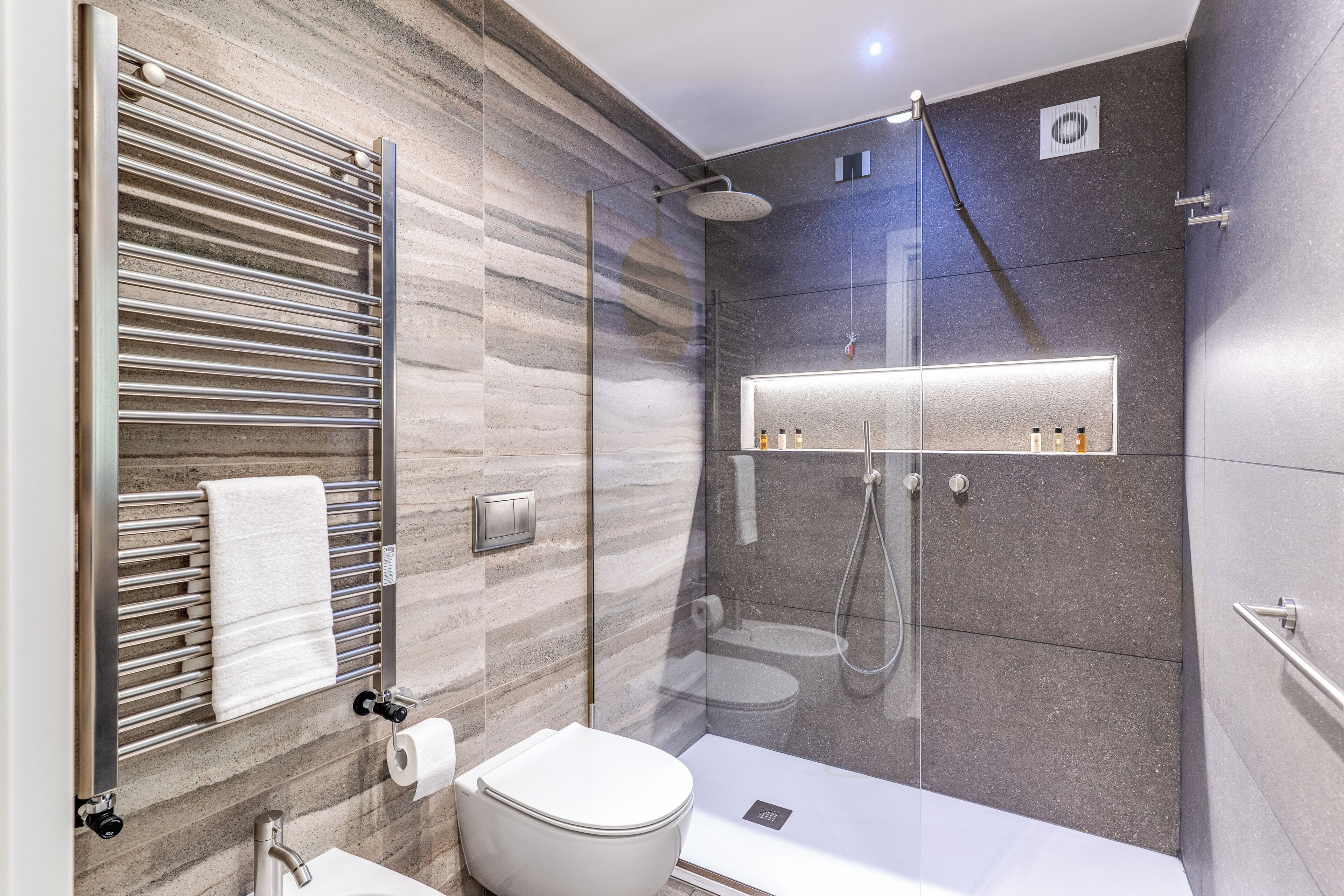 Un bagno moderno con doccia vetrata, un water e un porta asciugamani.
