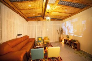 Ein Wohnzimmer mit Holzboden, einer Couch, einem Couchtisch und einem Fernseher, der ein Programm zeigt.