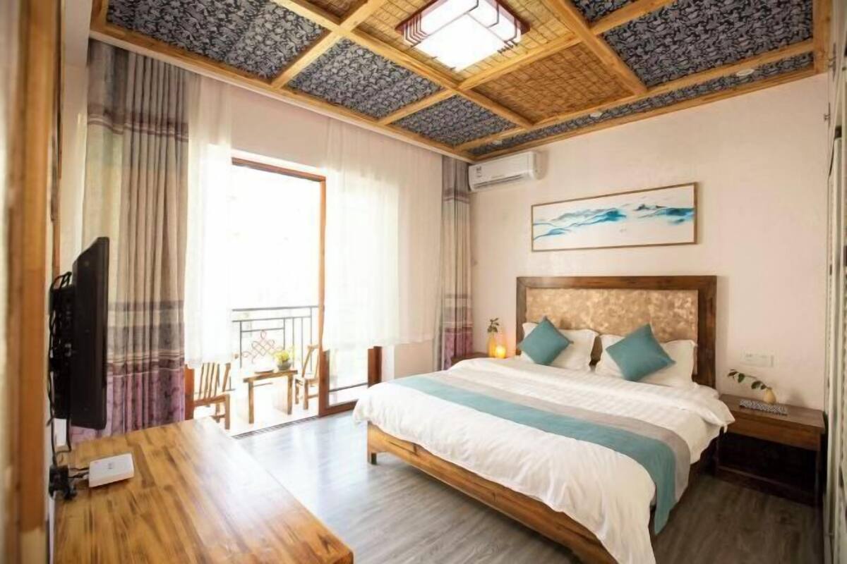 Een hotelkamer met een bed, een televisie, een bureau en een balkon met uitzicht.