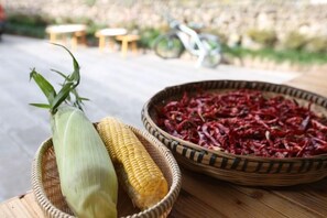 A basket with corn on the cob and dried red peppers on a wooden table. - Zhangjiajie perch tree house (Zhangjiajie)