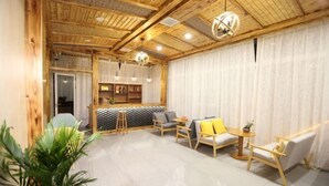 Een gezellige kamer met houten balken, een zithoek, een klein tafeltje en een potplant.