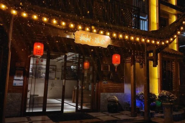 A traditional building with a sign, lanterns, and string lights.
