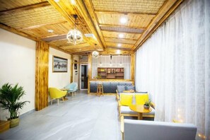 Ein Zimmer mit Holzboden, einem Essbereich mit gelb-weißen Möbeln und einer Bar mit einer Theke und Regalen.