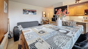Un salon chaleureux avec un tapis à motifs, un canapé gris et un vase blanc orné de fleurs.