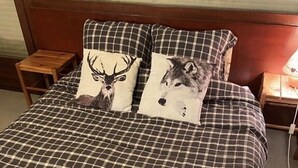 Un letto con una coperta a quadri e due cuscini con stampe di animali.