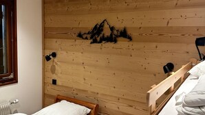 A bedroom with a wooden headboard, two beds, a radiator, and a window. - 2-room apartment in Châtel, sleeps 5 with WIFI and pets welcome (Châtel)