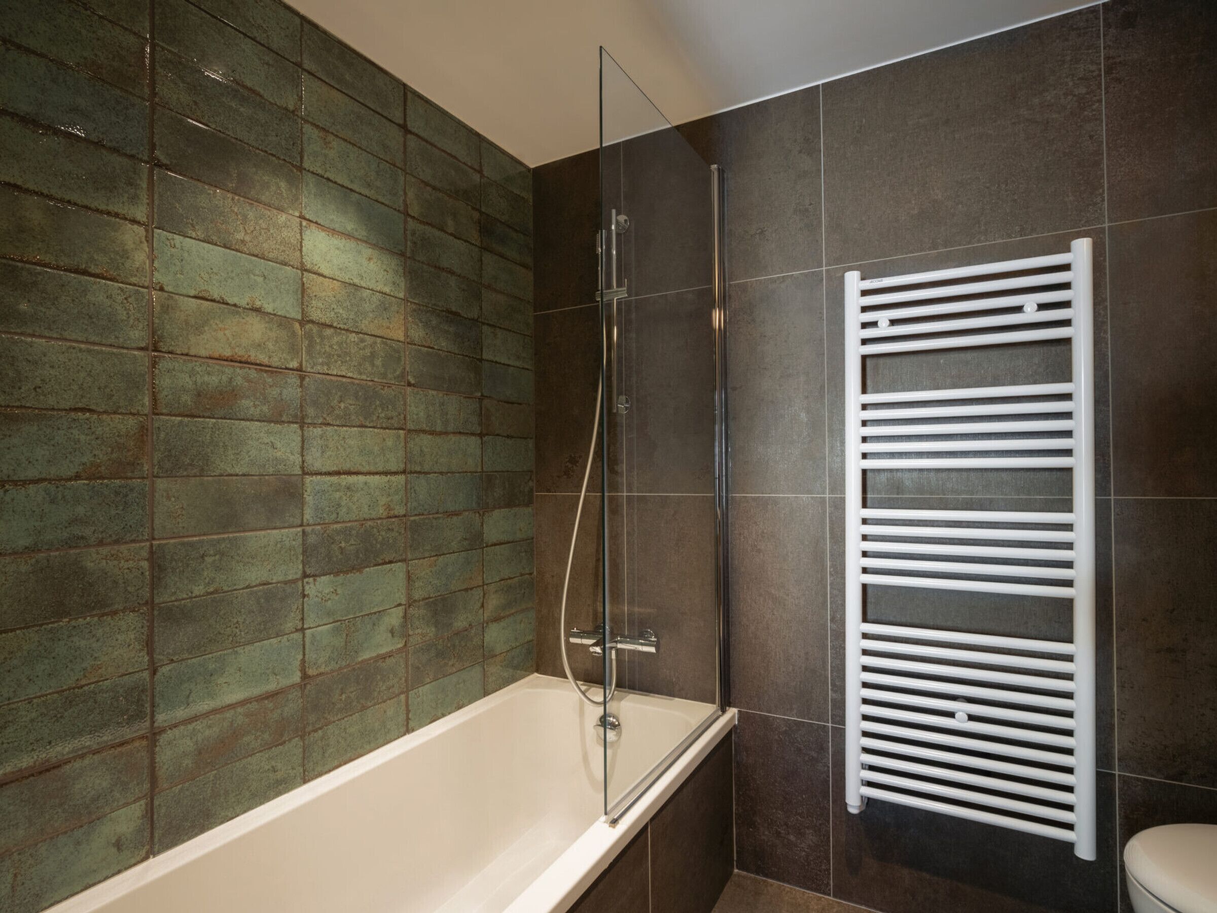 Une salle de bain moderne avec une baignoire, une cabine de douche en verre et un porte-serviettes blanc.