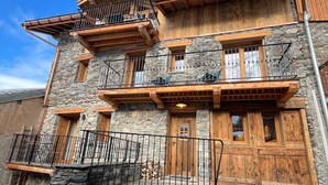 A multi-story stone building with wooden balconies, stone steps, and a wooden door. - Charming apartment for 4 near center (Saint-Martin-de-Belleville)