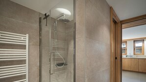 A modern bathroom with a glass-enclosed shower, a white towel rack, and a wooden vanity with a sink. - Charming apartment for 4 near center (Saint-Martin-de-Belleville)
