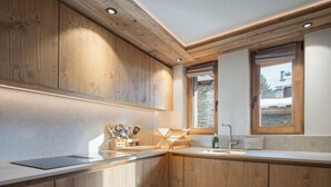 A modern kitchen with wooden cabinetry, a built-in oven, and a window with a view of the outside. - Charming apartment for 4 near center (Saint-Martin-de-Belleville)
