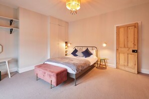 Une chambre à coucher comprenant un lit, une table de chevet, un banc, une armoire et une porte.
