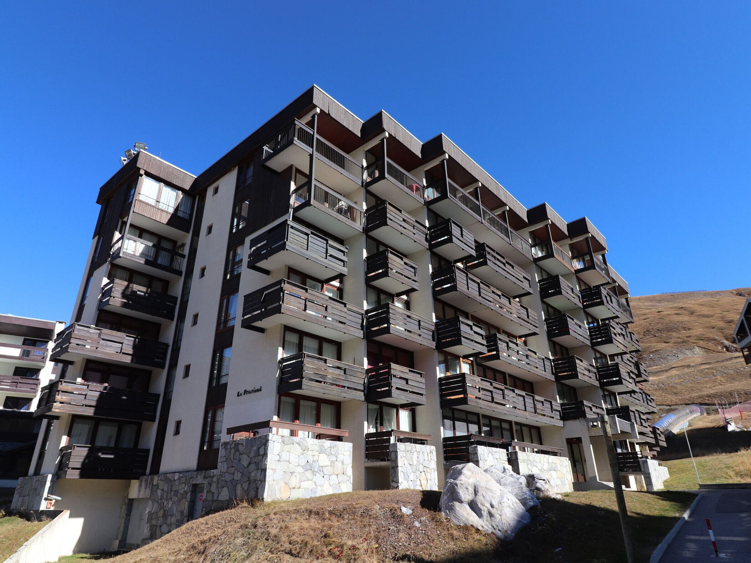 A multi-story building with balconies, stone base, and a clear sky.