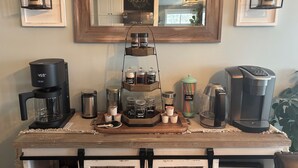 A coffee station with a coffee maker, a Kaffe, a thermos, and a coffee grinder.