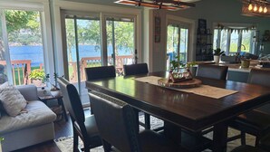 A dining area with a large wooden table, multiple chairs, and a view of the outdoors.